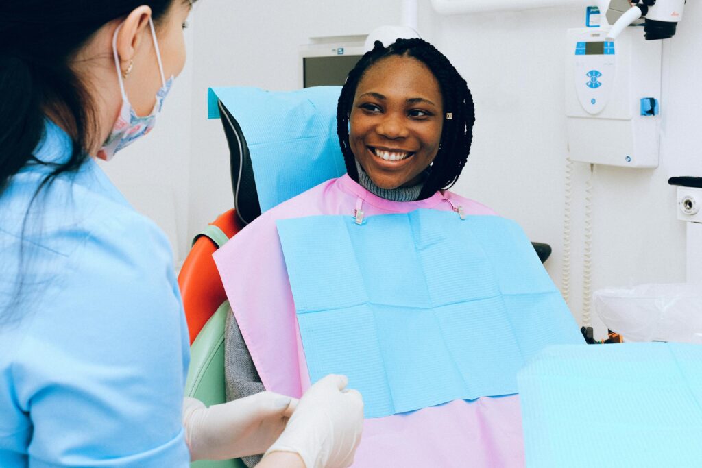 A smiling woman receives dental check-up from a practitioner in modern clinic.