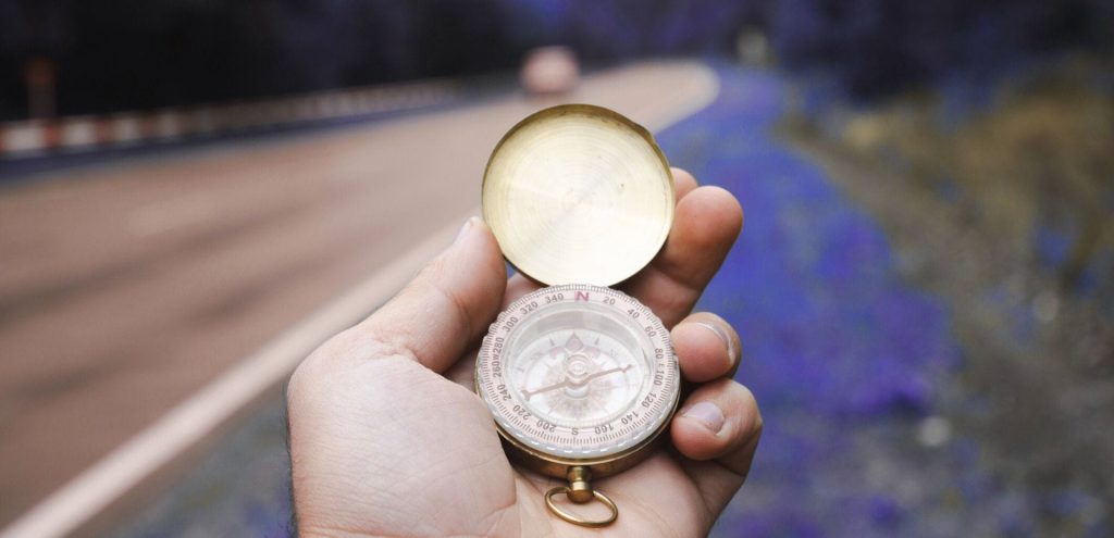 Hand holding compass near road symbolizing how digital strategy is your roadmap for 2026.